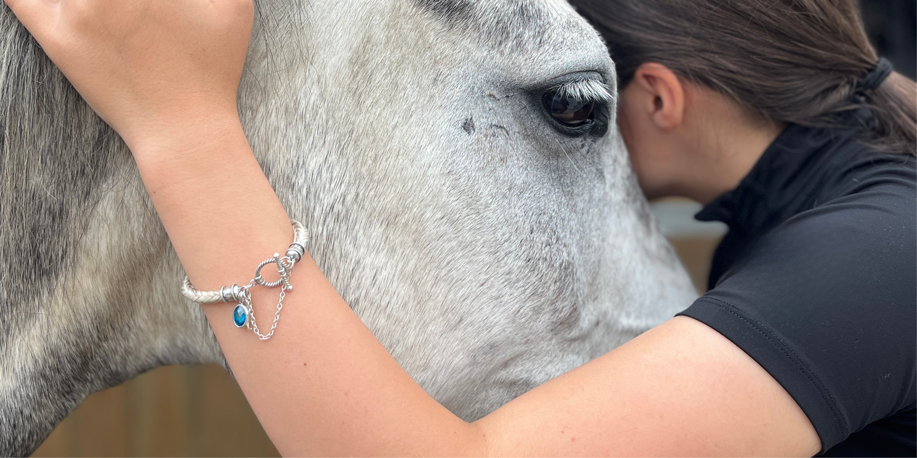 Close-up of a woman and her horse, showing a custom braided horsehair bracelet made from tail hair and sterling silver fittings
