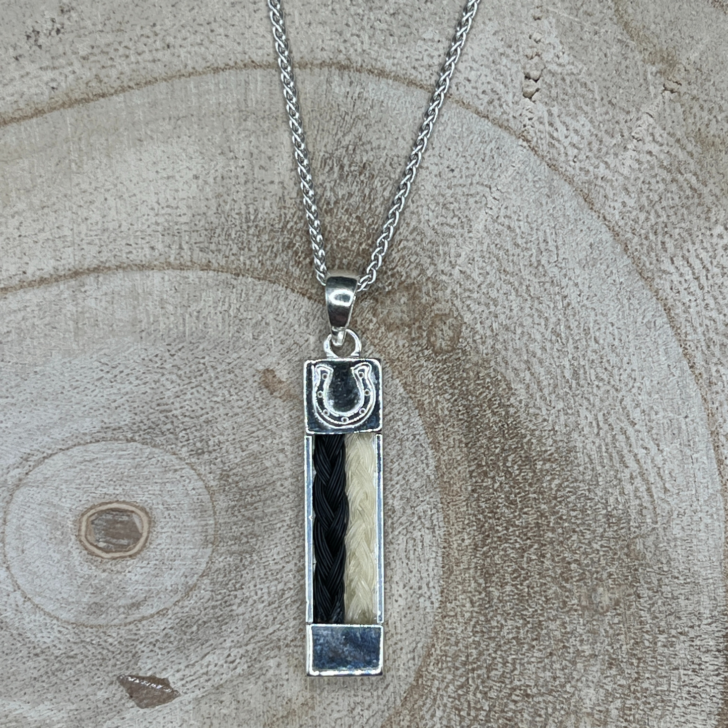 Handcrafted sterling silver bar pendant featuring two side-by-side braids made from black and cream horse hair.