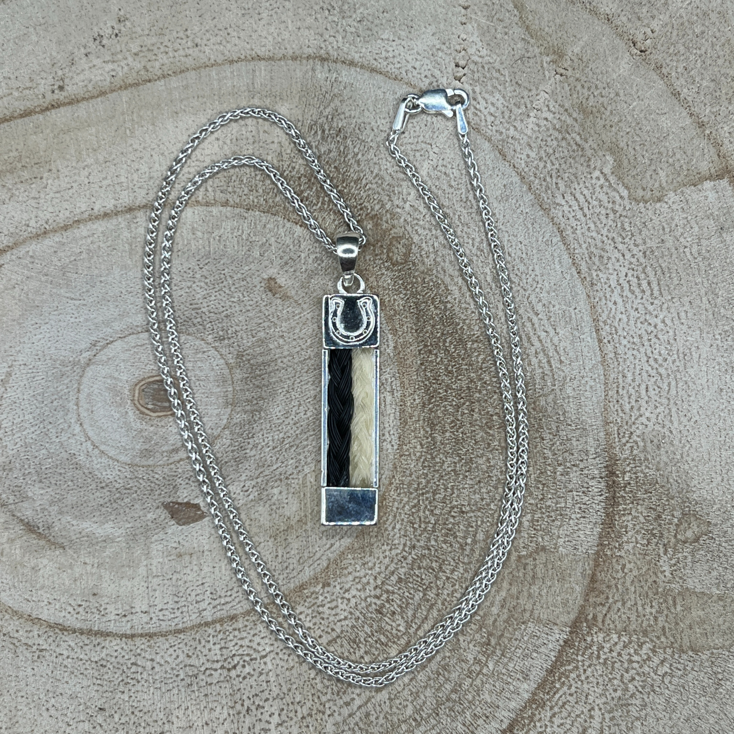Sterling silver bar pendant with two braided horse hair strands from different horses.
