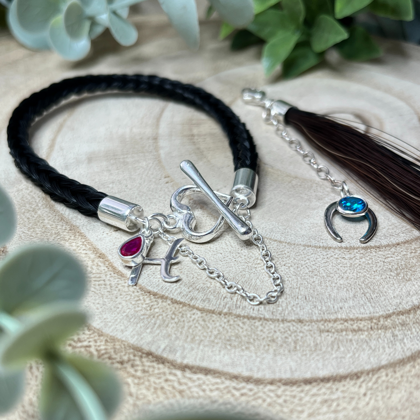 Bracelet with charms on a wooden surface with greenery