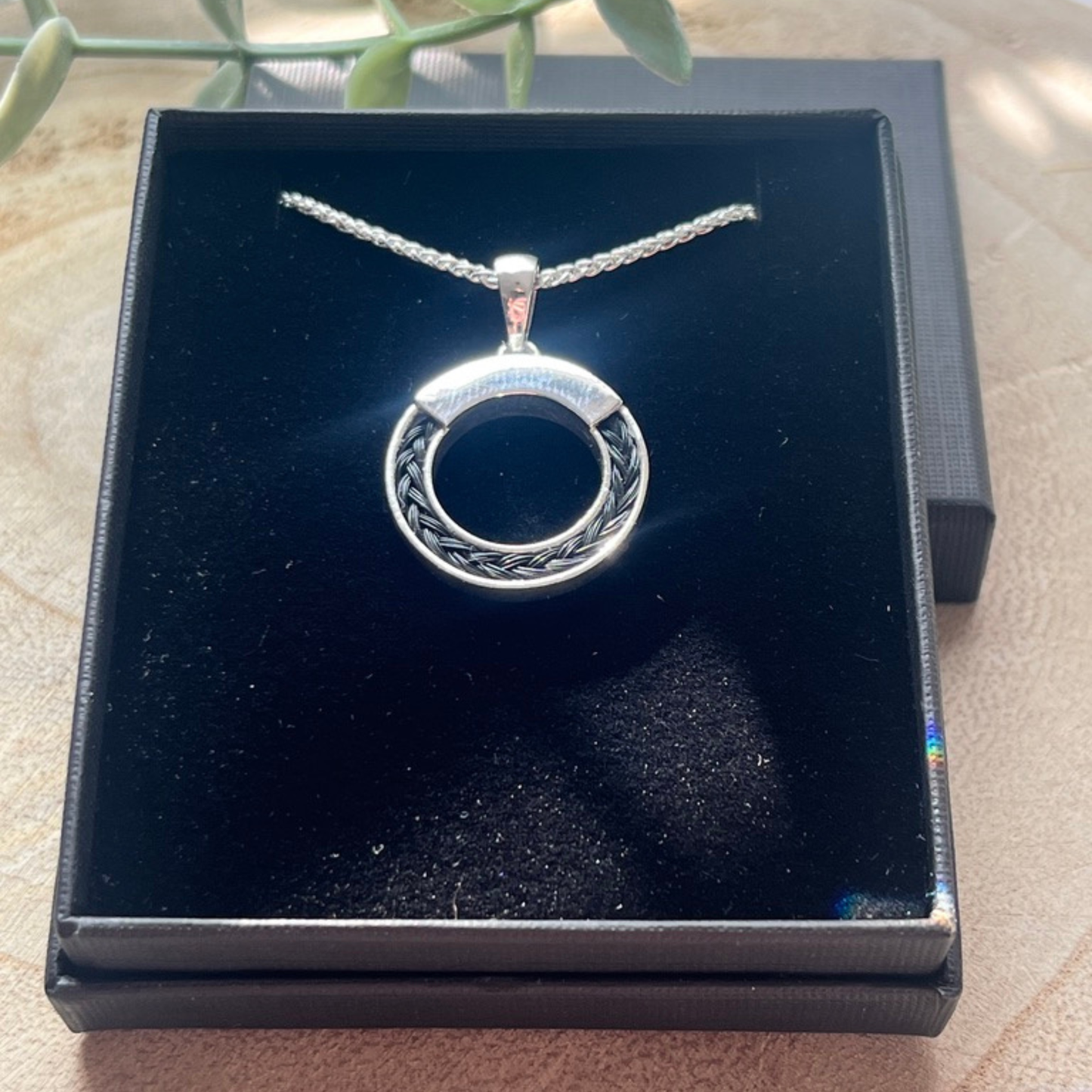 Silver necklace with a circular pendant in a black box